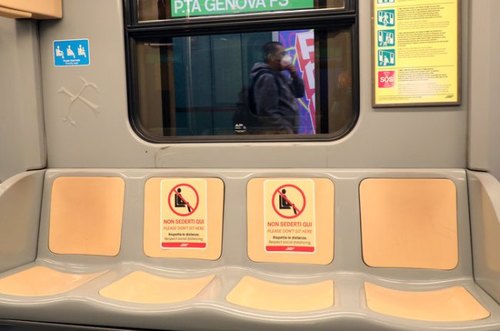 I cartelli apposti sui sedili della metro per il rispetto delle distanze 