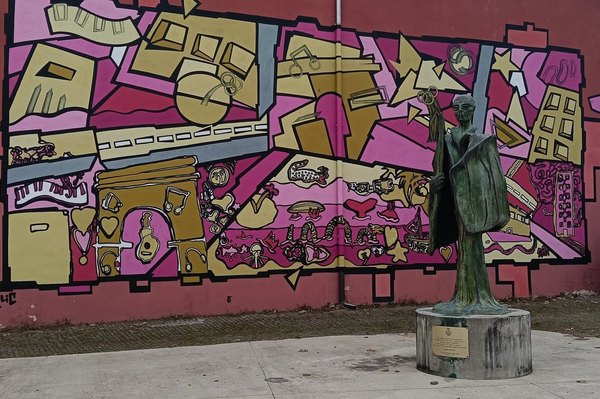 In primo piano il monumento a Sandro Pertini e sullo sfondo il murales commssionato dall'Amministrazione Comunale